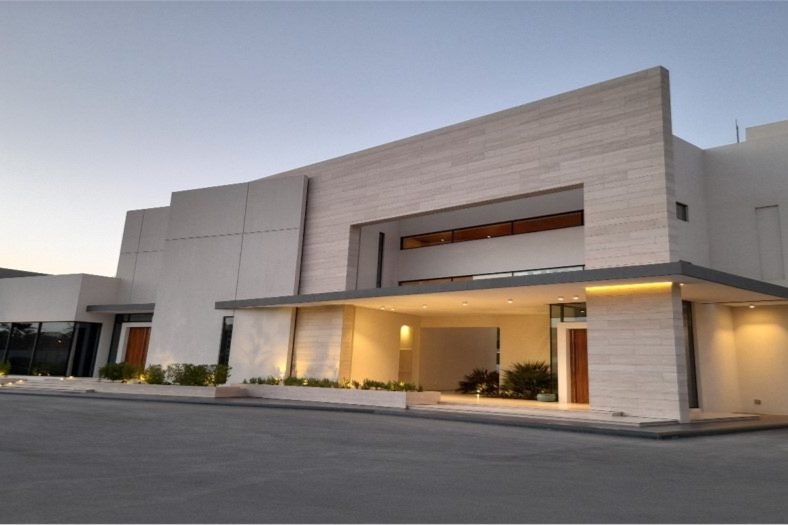 Modern stone-clad two storey luxury villa at dusk in Jasrah, Bahrain